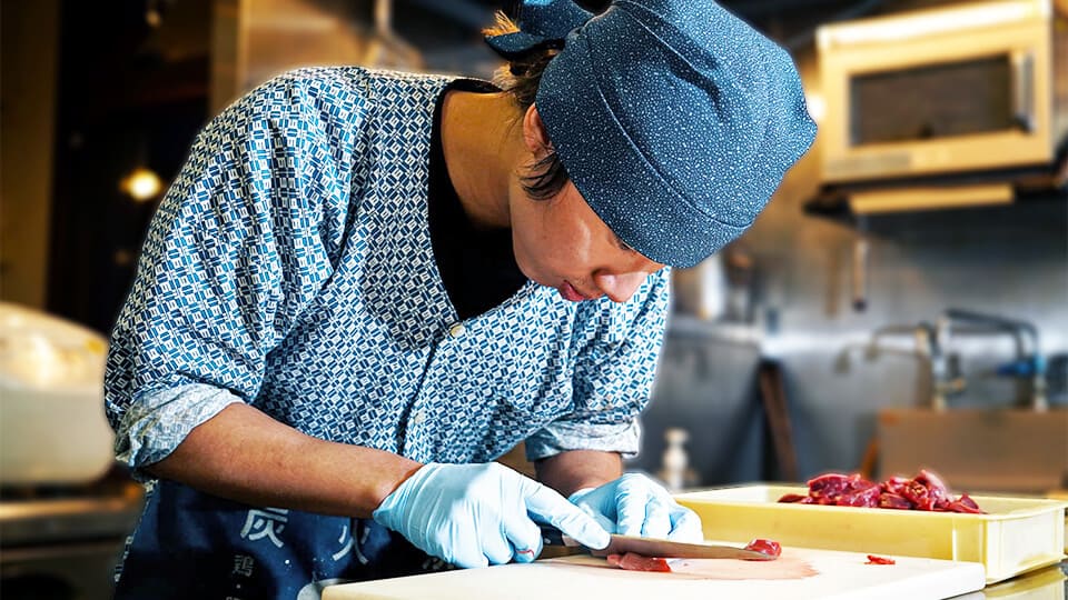 炭火焼酒房すいしんの男性アルバイトが調理でまかないを作っている。