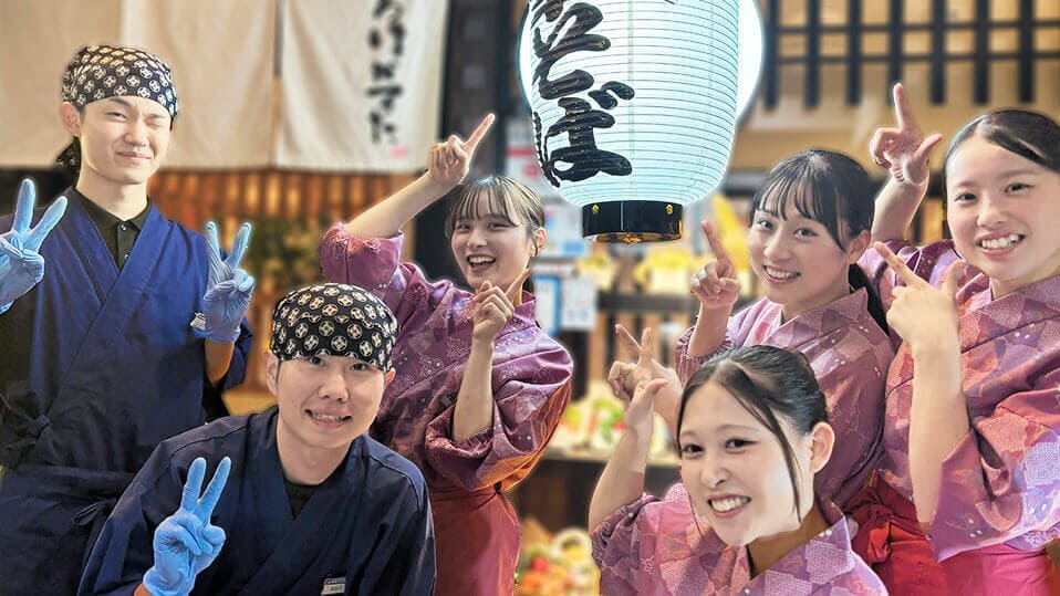 いろはかるた京都駅前店の学生アルバイトが仲良く店前で笑顔で写真をとっている。