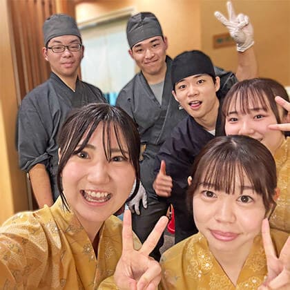 京すいしんの複数人の学生アルバイトがピースポーズをしている。