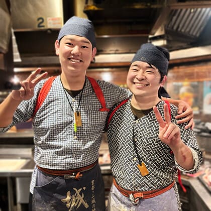 炭火焼酒房すいしんの男性アルバイトが肩を寄せ合って笑っている。